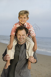 父亲和儿子在海滩肩上图片