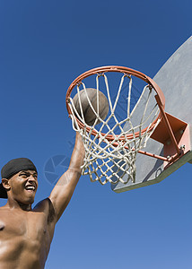 年轻不穿衬衫的非裔美国人在篮子里做一个灌篮射手图片