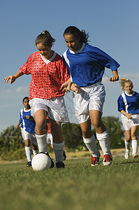 年幼女孩在田地上踢足球对抗天空竞争竞技项目用品服饰足球队运动队友赛事女性图片