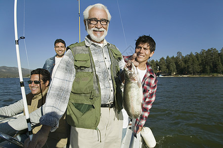 快乐的老年男子与背景中儿子一起抓新鱼的肖像图片