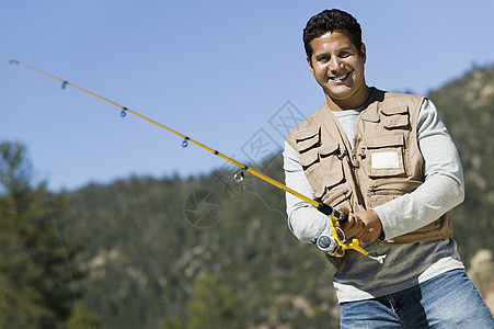一个快乐成熟的西班牙裔男子在阳光明媚的一天钓鱼的肖像图片