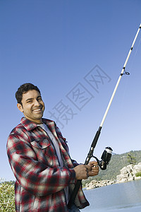 一个快乐的西班牙裔男人在湖边钓鱼的肖像图片