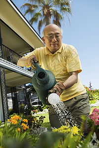 快乐的老人在花园里浇花水图片