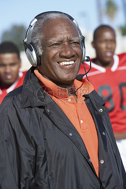 快乐的非洲裔美国高级教练穿戴耳机与背景球员一起使用耳机图片