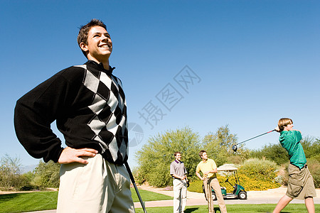 三个男高尔夫球手在看其他高尔夫球赛背景图片