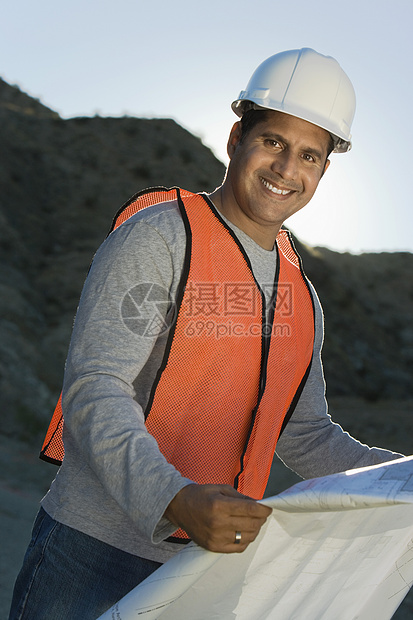 一名男子建筑师在建筑工地持有蓝图的肖像图片