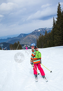 女孩在滑雪板上季节自由娱乐婴儿粉末晴天头盔背光运动越野图片