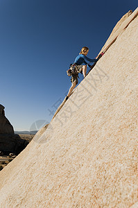 女青年在蓝天上攀岩的全长侧面图片