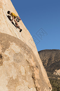 一个人在悬崖上攀爬的低角度视野 与清蓝天空相对男性空闲全身空格岩石表面攀岩年轻人消遣娱乐图片