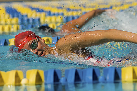 一个在游泳池游泳的年轻女子的侧视角图片