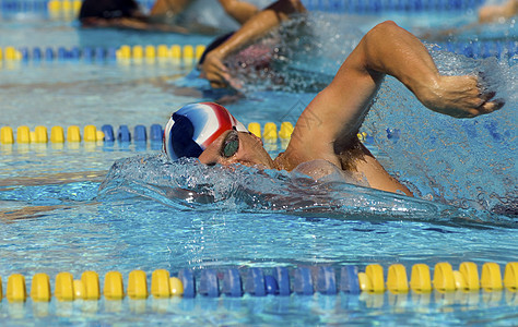 男性游泳运动员与背景中的其他参与者竞争游泳比赛图片