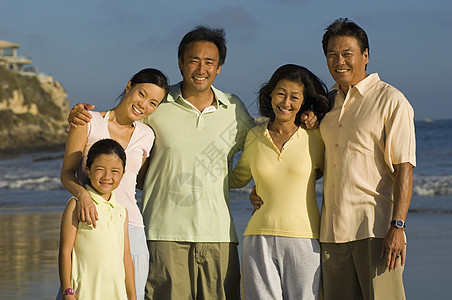 快乐家庭与女孩在海滩上摆姿势的肖像图片
