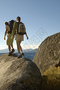 海岸在巨石上行走的一对远足夫妇全长后方视线图片