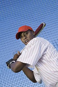 一个年轻的棒球运动员的低角度视角 与网对打图片