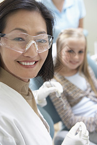 一名女牙医的肖像 该名女牙医准备接受检查 而小女孩则坐在背景中图片