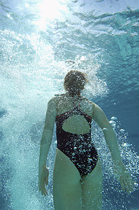 在水下游泳的年轻女子的近视图片
