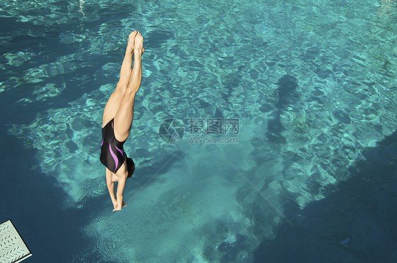 活跃的女性潜水员冲进游泳池 倒入游泳池图片
