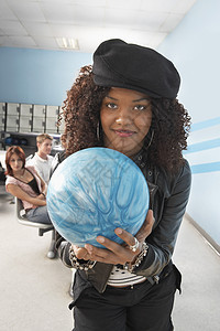 一位年轻的非裔美国女子的肖像 她的朋友在保龄球馆握着球图片