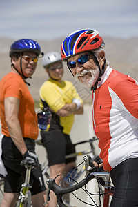 一位快乐的老年男性骑自行车运动员的肖像 朋友站在幕后图片