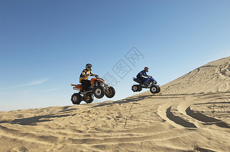 两个男人在沙漠中骑四轮自行车的侧边视线图片