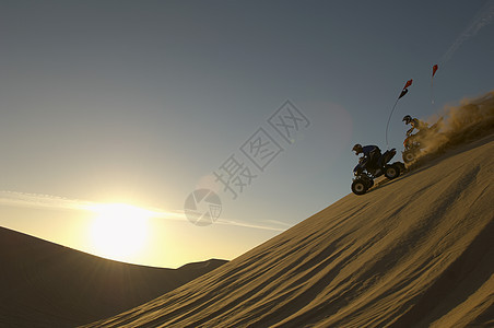 日落时男子在沙漠骑自行车图片