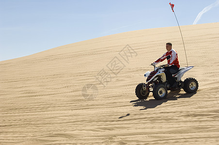 一个男人在阳光明媚的白天 在沙漠中骑四轮自行车的侧面景色行动男人司机速度赛车车辆骑士天空旗帜越野图片