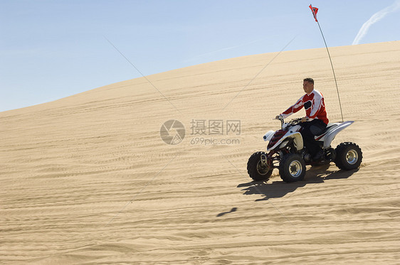 一个男人在阳光明媚的白天 在沙漠中骑四轮自行车的侧面景色行动男人司机速度赛车车辆骑士天空旗帜越野图片