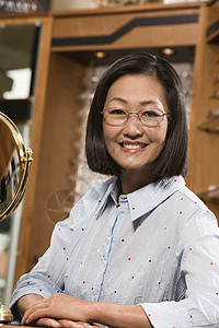 一个快乐成熟的中国女人在店里 试戴眼镜的肖像图片