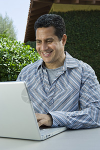 在笔记本电脑上工作的快乐成熟男子图片