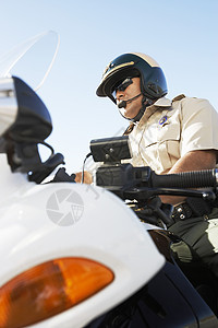 一名坐在摩托车上对天的警察低角度视角(仰望天空)图片