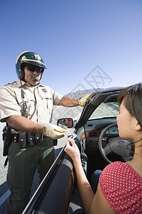 在街上检查女性驾照的成年警察男子图片