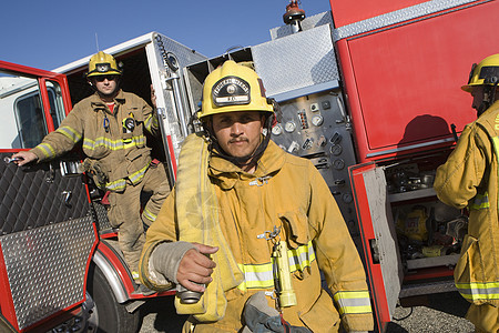 一名成熟的消防工人和背景中的同事的肖像消防队员情况中年软管男子卡车制服运输灾难消防车图片