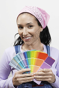 一位带着油漆颜色样本的笑着女人的近镜肖像图片