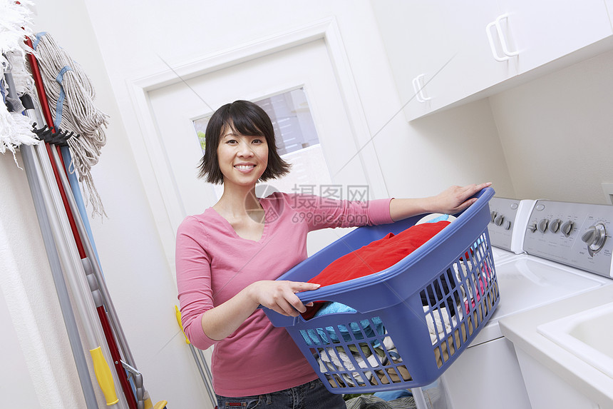 亚洲妇女用洗衣机携带洗衣篮的亚洲妇女的纵向肖像图片