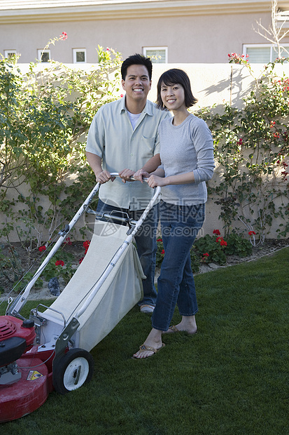 一对快乐的夫妇园艺和割草机的肖像图片