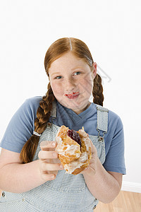 对一个在白色背景下 拿着糕饼的超重女孩的肖像图片