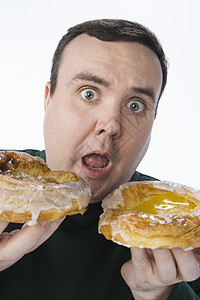 令人惊讶的中年男子抓着甜甜圈的肖像 这些甜甜圈被白种背景隔绝图片