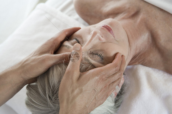 一名老年妇女在温泉疗养时接受头部按摩的高角度视角图片