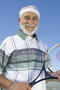 一个快乐的老年男子的肖像 拿着网球棍对着天空图片