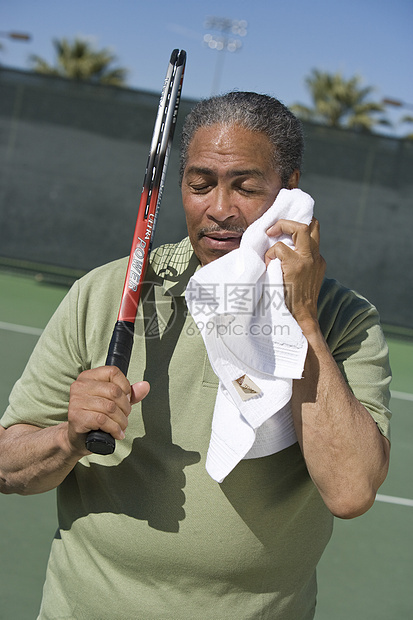 高级男性网球运动员用餐巾纸擦脸图片