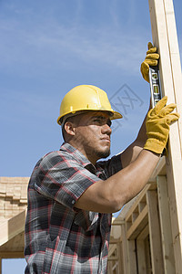 男性工人用精神水平检查垂直木柴的垂直水平图片