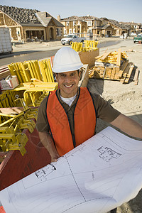 建筑设计师的肖像和建筑工地蓝图图眼神职业中年工作微笑建筑工人前景防护安全帽房子图片