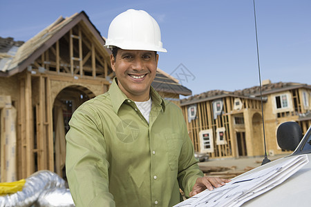 建筑工地身着硬帽的快乐成熟男性建筑师肖像图片