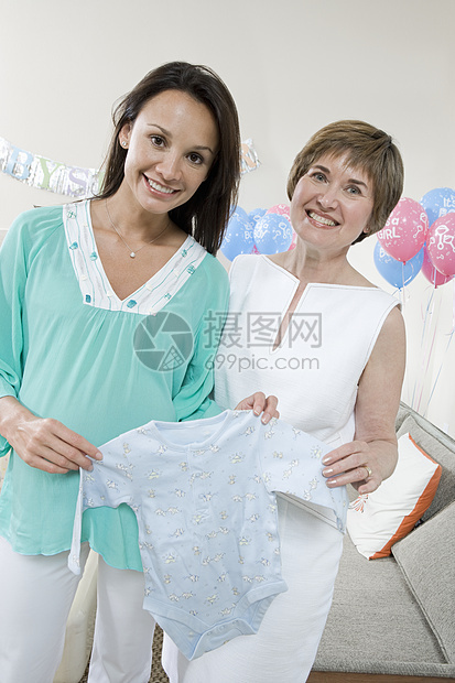 母亲在婴儿淋浴时带着婴儿衣服的幸福孕妇的肖像图片