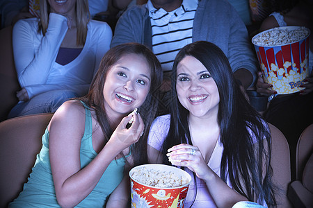 年轻朋友在电影院看电影时吃爆米花图片