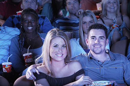 坐在剧院看电影的一对年轻夫妇肩膀旁团结成人享受活动中年电影夫妻上衣朋友们露肩图片
