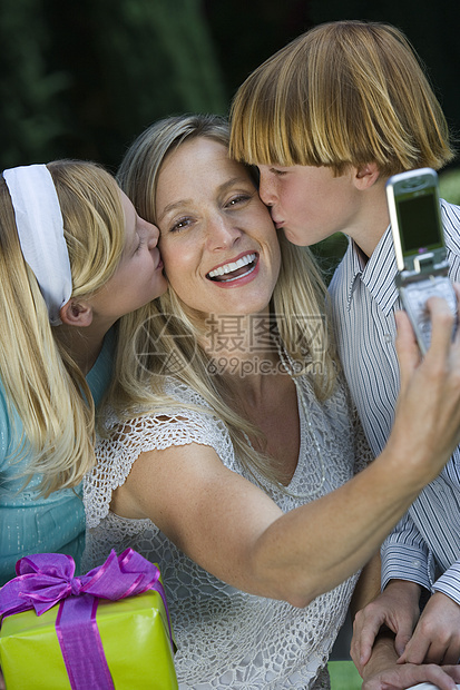 快乐母亲的肖像在孩子生日时亲吻她的脸颊时点击自拍照片图片