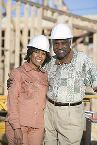 快乐的非洲裔美国高龄情侣在不完整房屋前穿着硬头巾的肖像图片