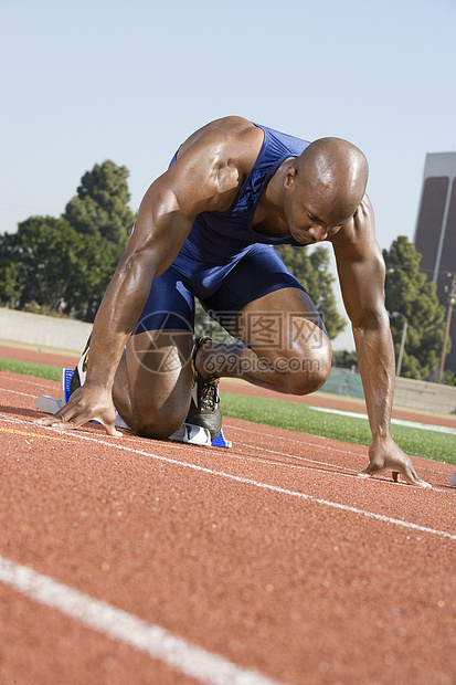 一名非裔美国男子在赛马场的起跑位置上全长跑步图片