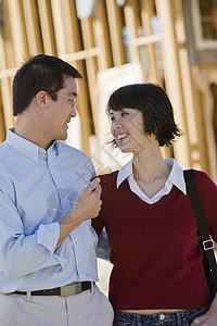 在建筑工地站立时友好聊天的中华夫妇图片
